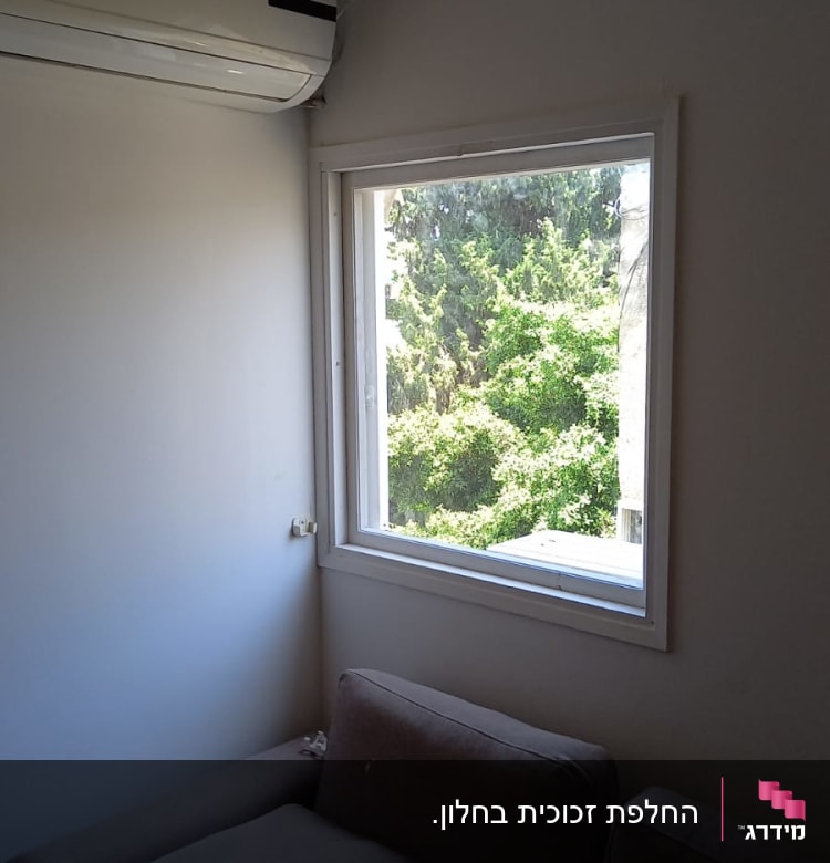 חלון זכוכית עם נוף עצים ירוקים בחוץ